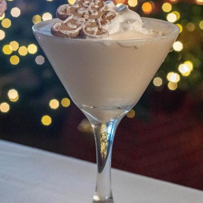 Creamy cocktail in a martini glass topped with whipped cream and a gingerbread cookie.