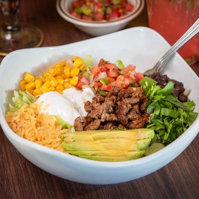 Salad with steak, beans, lettuce, avocado, cilantro, rice, corn, cheese, sour cream, and salsa.
