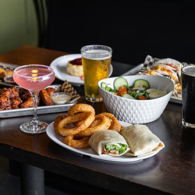 Assortment of dishes served on the table with two glasses of beer and a cocktail.