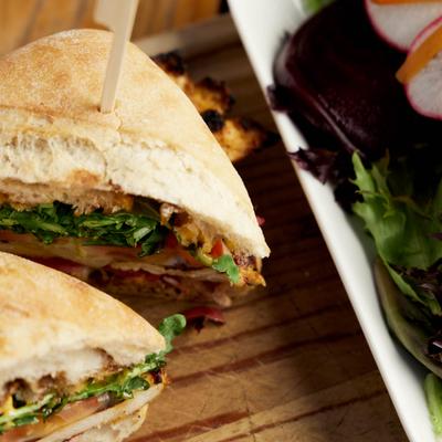 Grilled chicken sandwich and salad, close up.