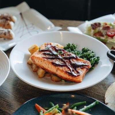 Glazed Salmon with roasted potatoes and broccolin, alongside other dishes.
