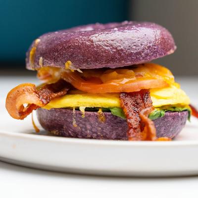 Breakfast Bagel with scrambled egg, tomato, spinach, cheese, and bacon.