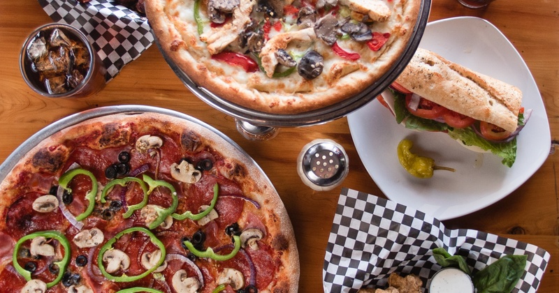 Two different types of pizza and a sandwich on a side