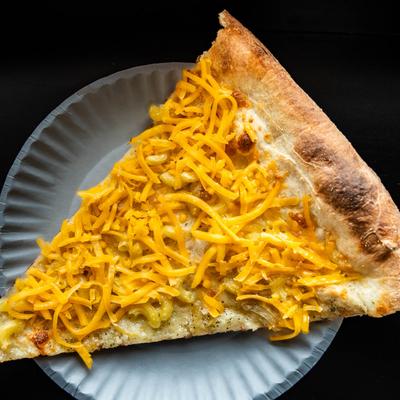 A slice of white pizza with macaroni, mozzarella, and cheddar cheese.
