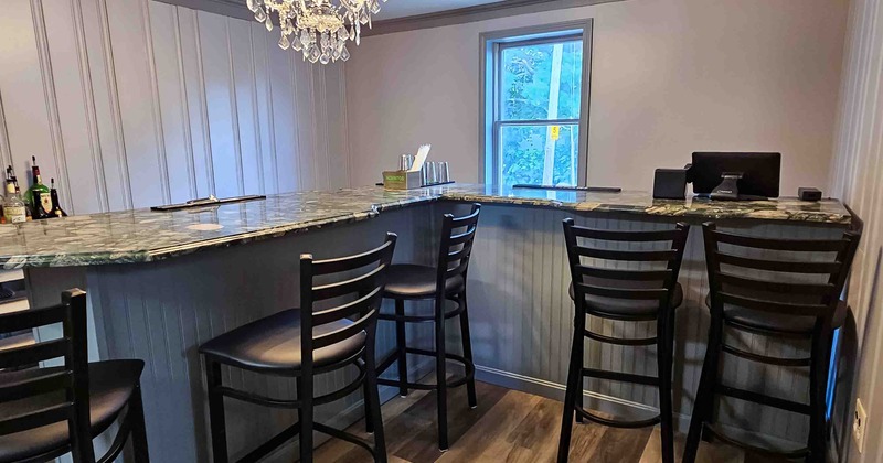 Bar area with a marble countertop, four chairs, a crystal chandelier, and a window