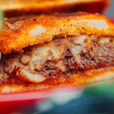 Close-up of a beef torta sandwich with melted cheese.