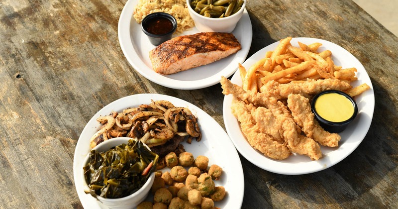 Grilled salmon with rice and green beans, beside chicken tenders with fries, and fried okra