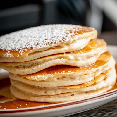 Stack of pancakes dusted with powdered sugar.