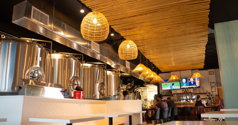 Interior features large brewing tanks visible to customers, a bar area, and dining tables