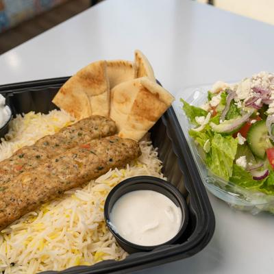 Ground chicken kabob with sides of, salad, rice, pita and tzatziki