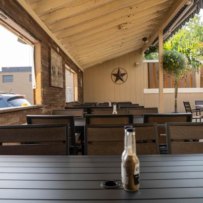 Covered wooden patio with dark dining tables and a rustic star decoration on the wall.