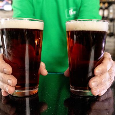 Staff member holding two glasses of dark beer.