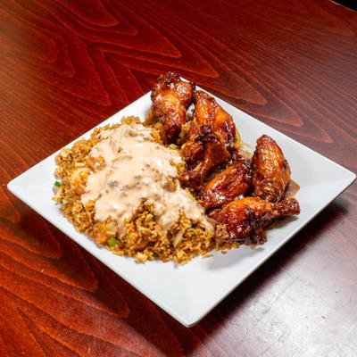 Chicken wings served alonside fried rice topped with creamy sauce.