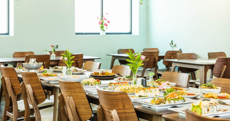 Interior, dining area, closeup on the long table setup with various dishes served