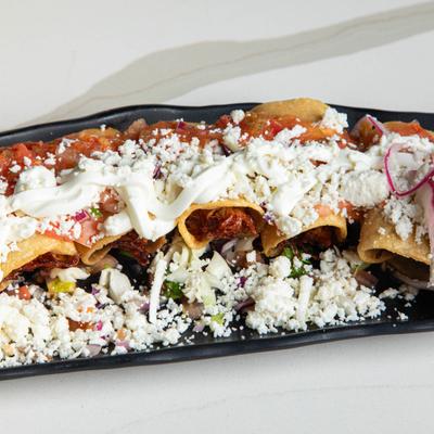 Flautas topped with crumbled cheese, salsa and sour creme.