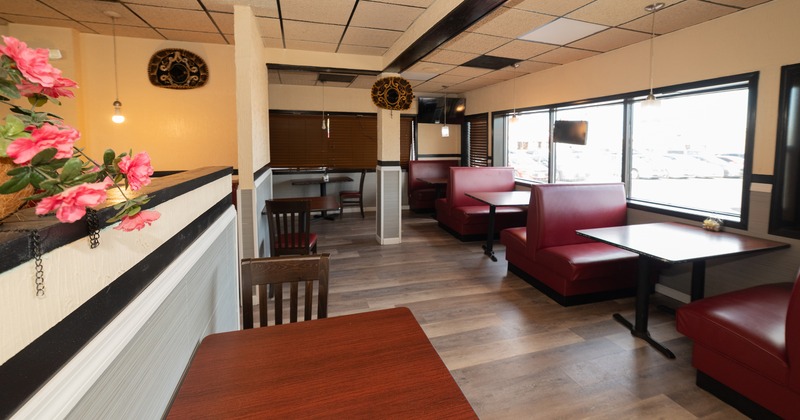 Restaurant interior with red booths, wooden tables and large windows.