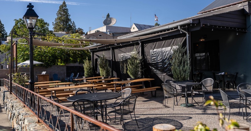 Outdoor café seating area with tables, chairs and a canopy for shade