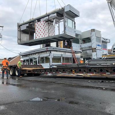 A crane lifts a large box onto a truck