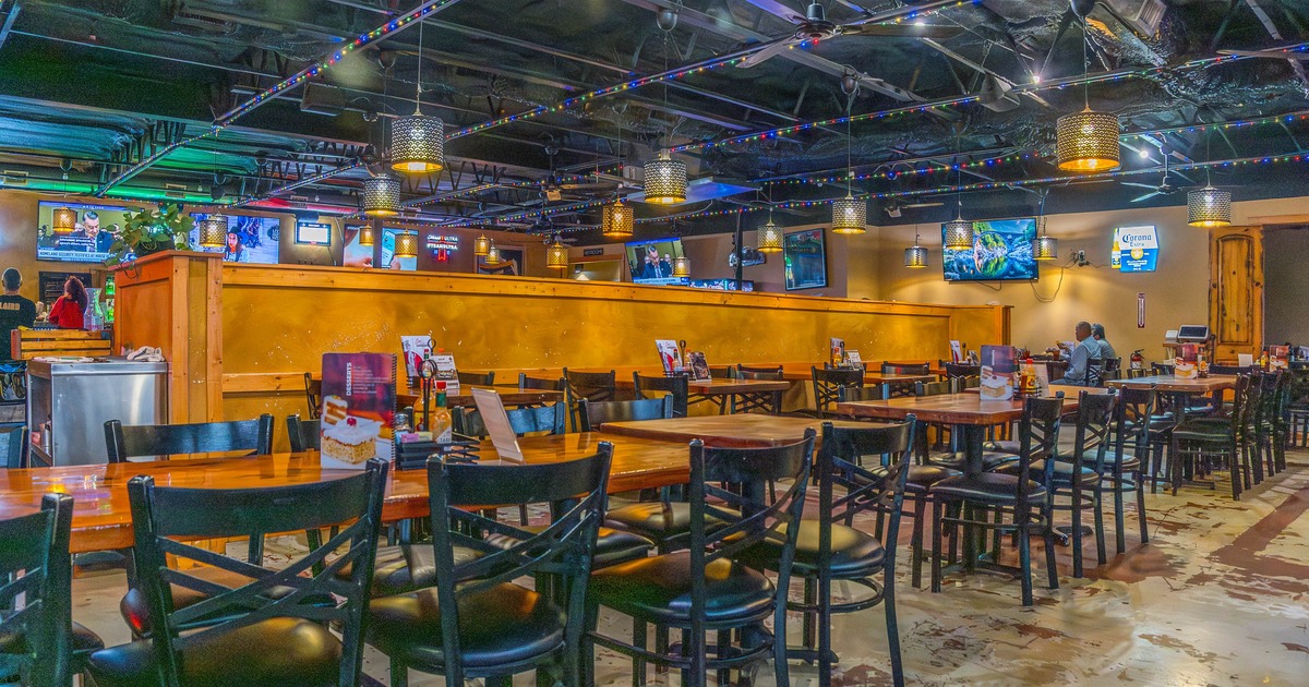 Inside, seating area with wooden tables and chairs, TVs on the wall
