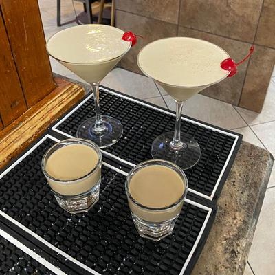 Two cocktails in martini glasses alongside two shooter cocktails.