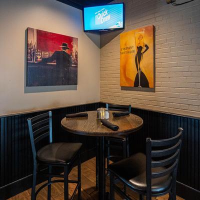 A table with two chair in a wall corner decorated with canvas prints.