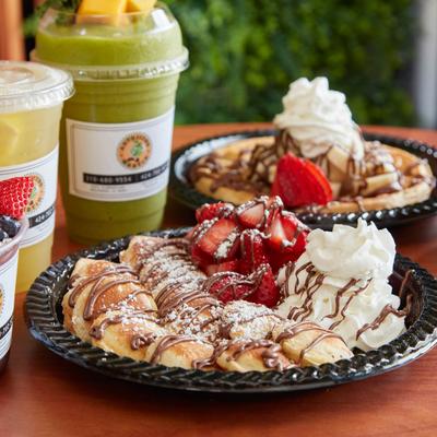 Mini pancakes topped with strawberries and whipped cream, served with fruit smoothies.