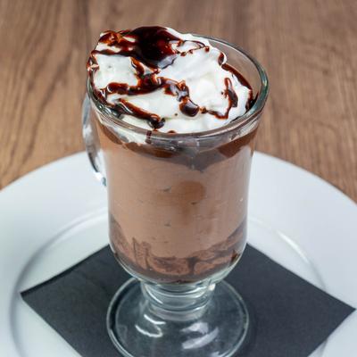 Chocolate Mousse served in a glass, topped with whipped cream and chocolate sauce drizzle.