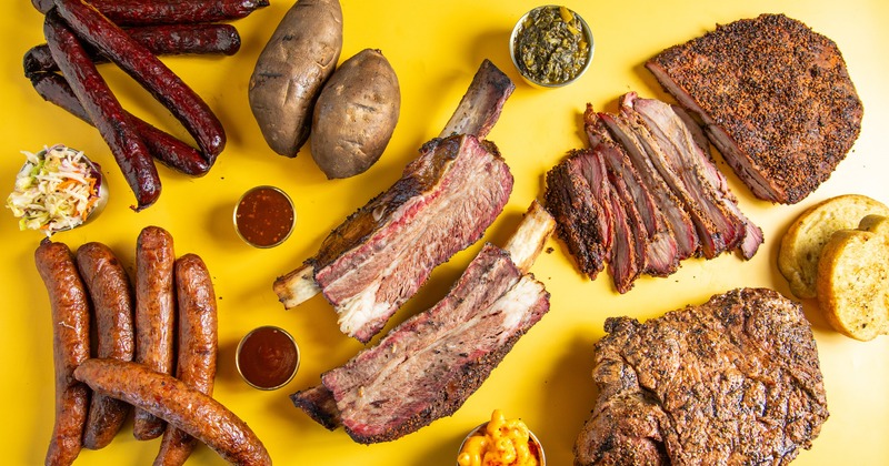 A spread of assorted meats, sides, sauces, and sausages on a yellow background