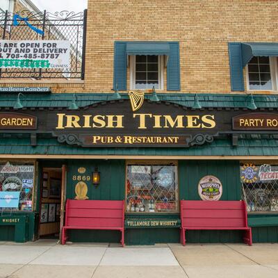 Exterior Iris Times Pub and Restaurant entrance and two red benches.