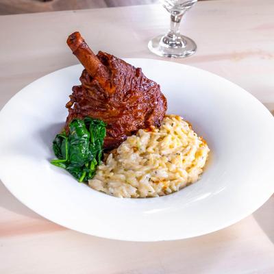 Lamb Shank served with spinach and creamy Orzo.