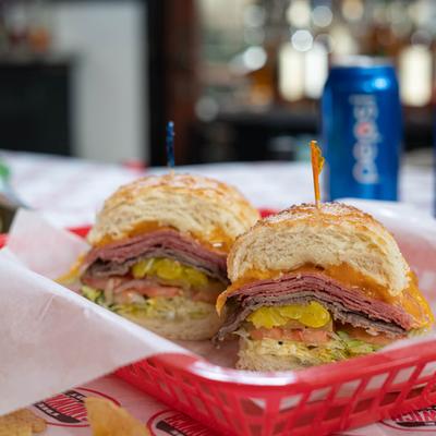 Sandwich with hot pastrami, roast beef, cheese, pickles, and lettuce.