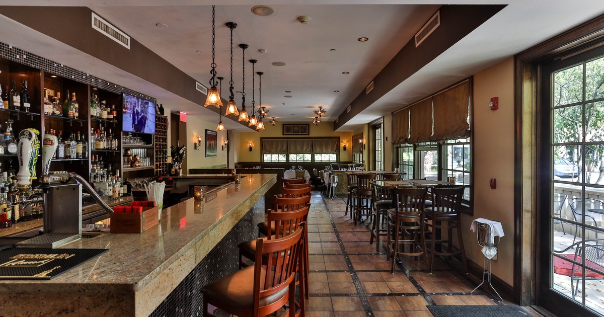 Interior of a modern bar with a granite counter, bar stools, pendant lights and large windows