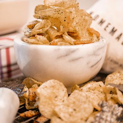 Seasoned potato chips served in a white marble bowl.