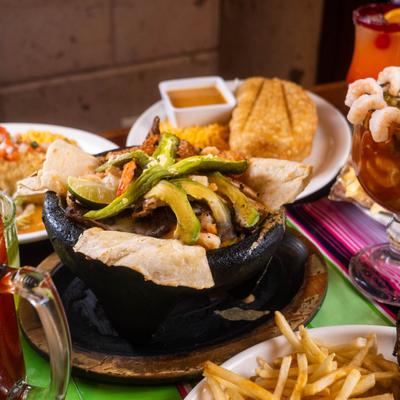 Molcajete dish served in a volcanic rock bowl, alongside other dishes.