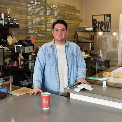 An employee posing for a picture behind order counter.