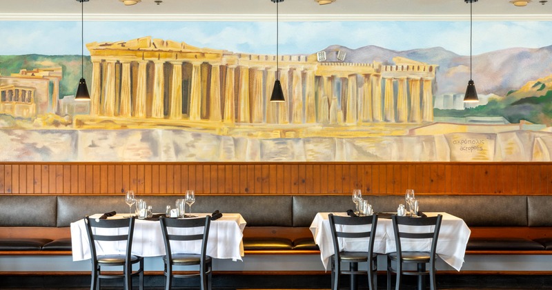 Interior, banquette seating with tables and chairs in front of a wall mural
