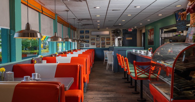 Interior of a classic diner with red and white booths and orange stools