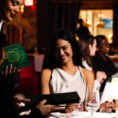 Hostess at Calle Dragones presenting menus for guests.