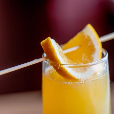 Mimosa garnished with slice of orange, close-up.