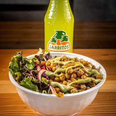 Chickpea bowl served on the table beside a bottle of pineapple soda.
