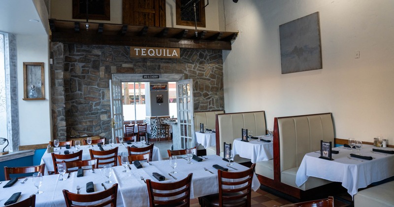 Interior, white cloth tables for six and eight, seating booths with set up tables