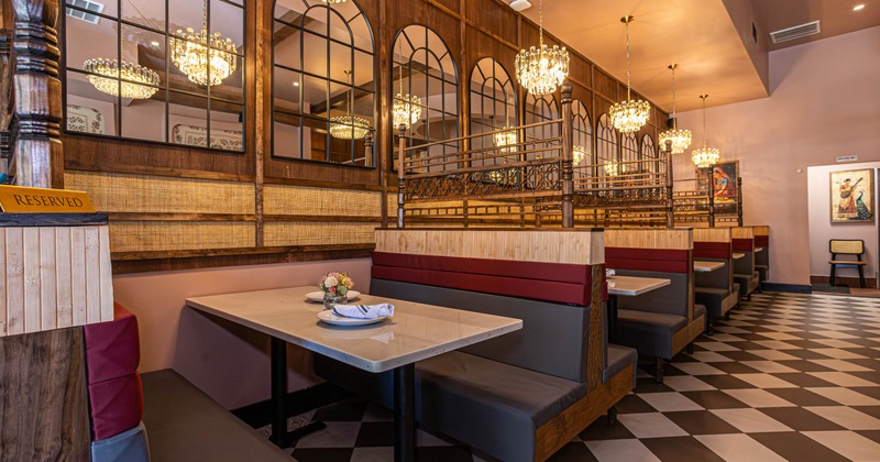 Restaurant interior with booths, chandeliers and checkered flooring.