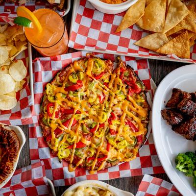 Whole pizza served alongside chips, a drink, and a side plate with meat and broccoli.