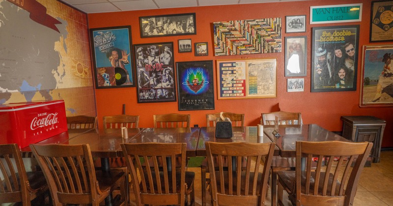 Restaurant dining area with wooden tables and chairs and walls covered in vintage rock-music memorabilia