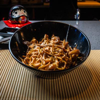 Bowl of creamy noodle stir-fry on a bamboo mat.