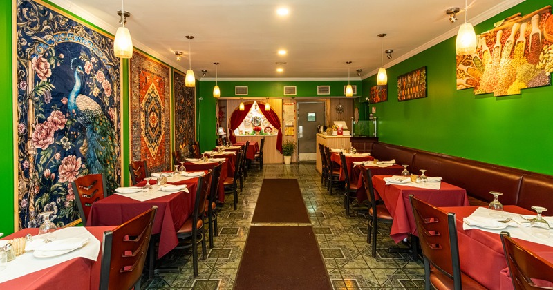 Interior, red draped tables, colorful tapestries on one wall, and spice artwork on a green wall