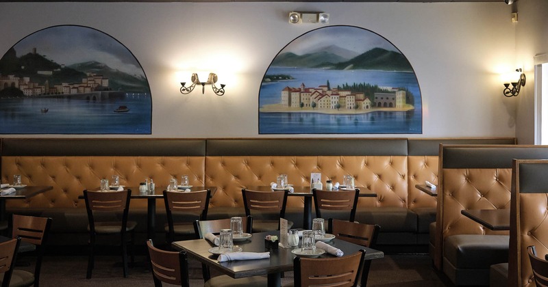 Dining area with set table and seating, a wall is decorated with serene murals of a bay