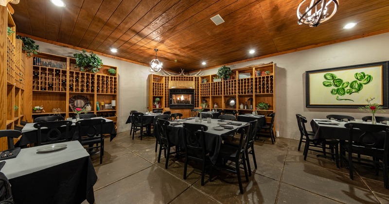 Interior, dining area, tables and chairs ready for guests, fireplace, large wine shelves