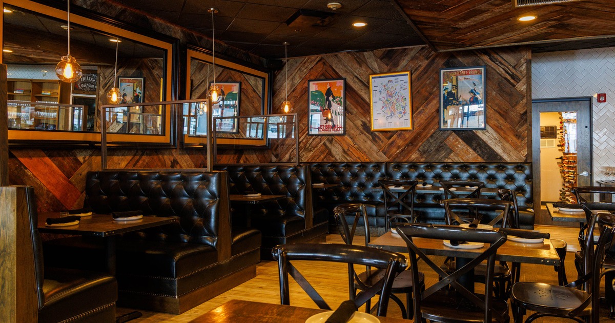 Restaurant interior with dark leather booths, wooden accents, and framed artwork.