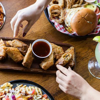 Platter of egg rolls with a dip, alongside other food items.